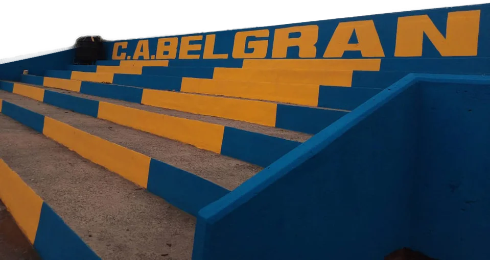 Tribuna pintada de azul y amarillo con la inscripción C. A. Belgrano